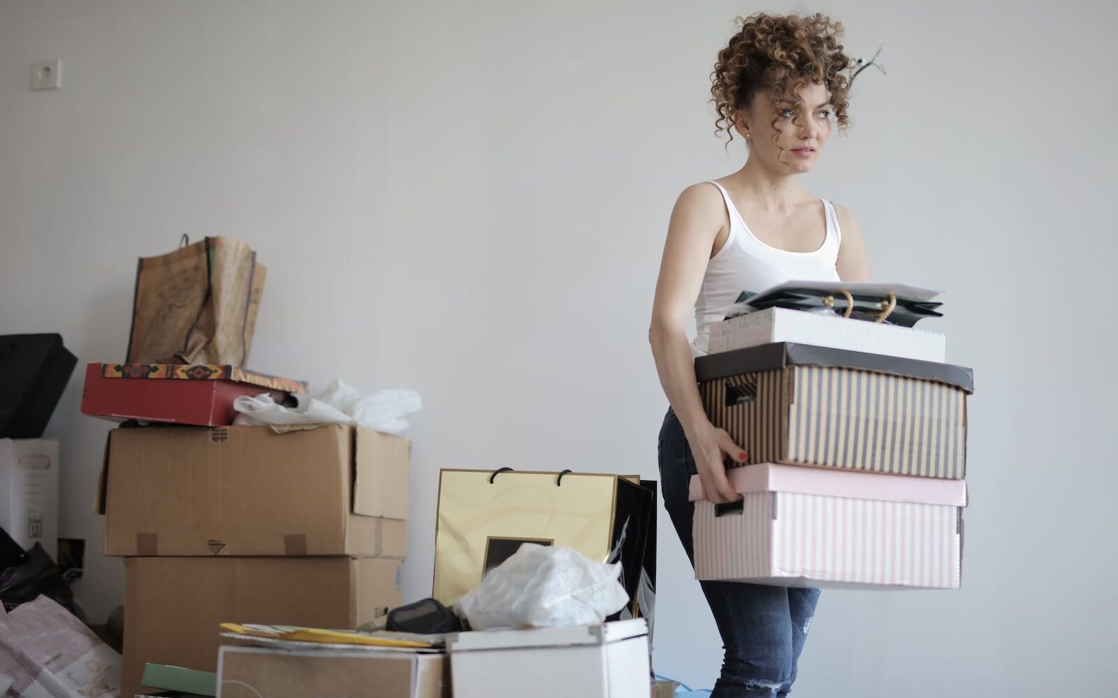 Concentrated woman carrying stack of cardboard boxes for self storage